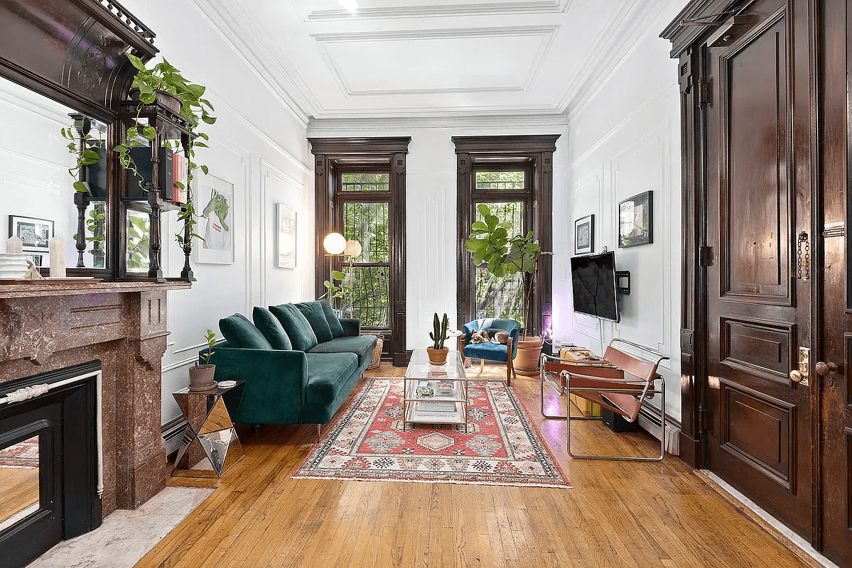 the living room with a mantel, wood floors and moldings