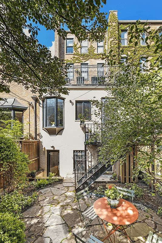 rear of house with paved garden and plantings