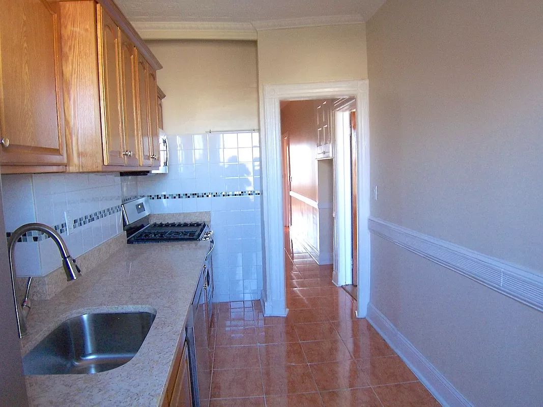 kitchen with wood cabinets and white tile walls with green accent tile