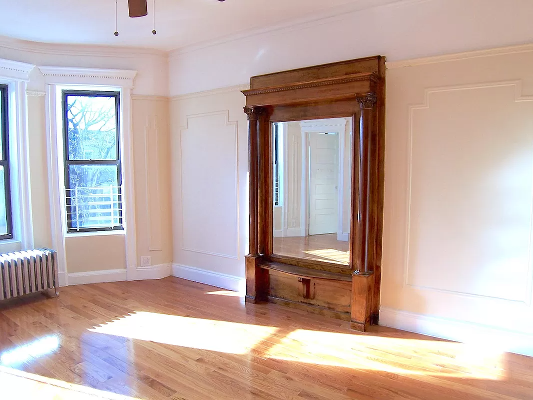 crown heights apartment - living room with pier mirror, wall moldings and a ceiling fan