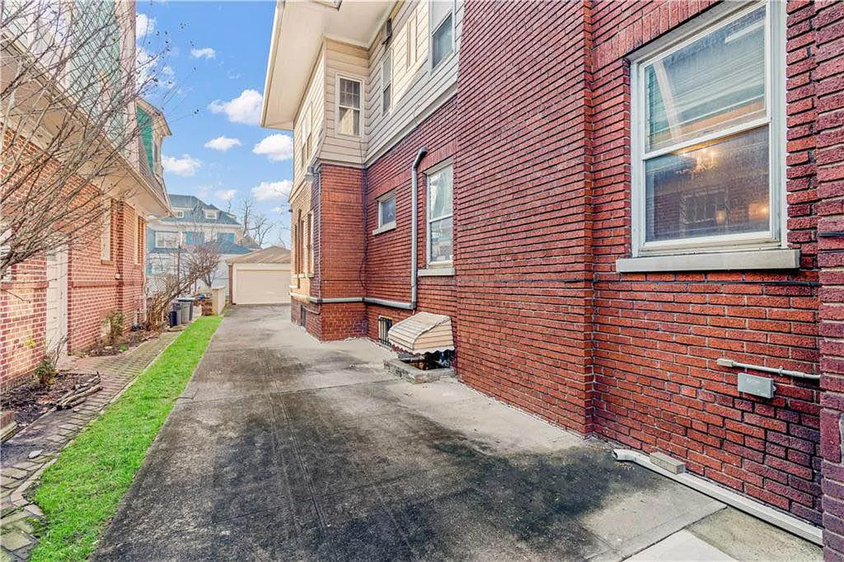 cement driveway with view of garage at rear of yard