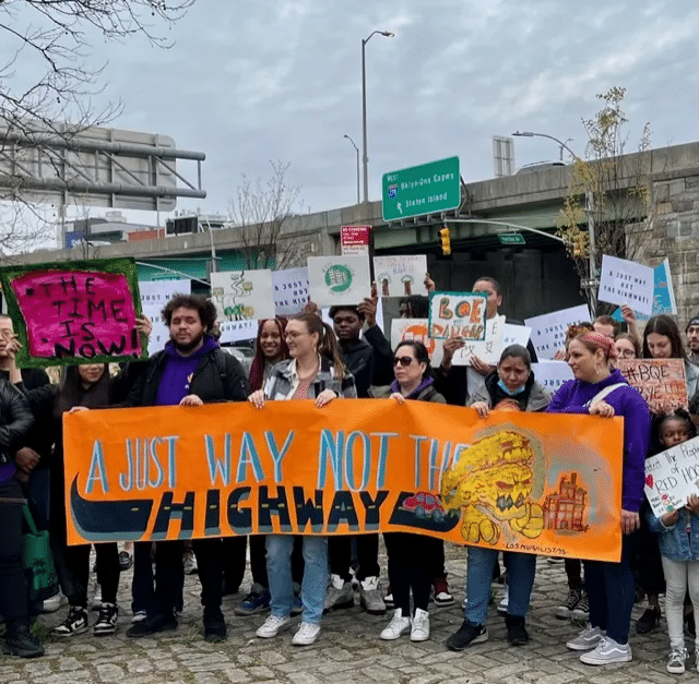 people at the rally holding a highway saying a just way not the highway