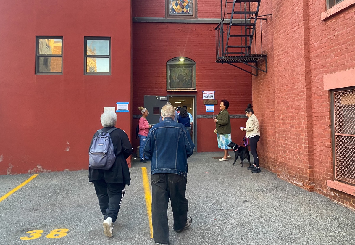 people approaching walking into a building for the community meeting