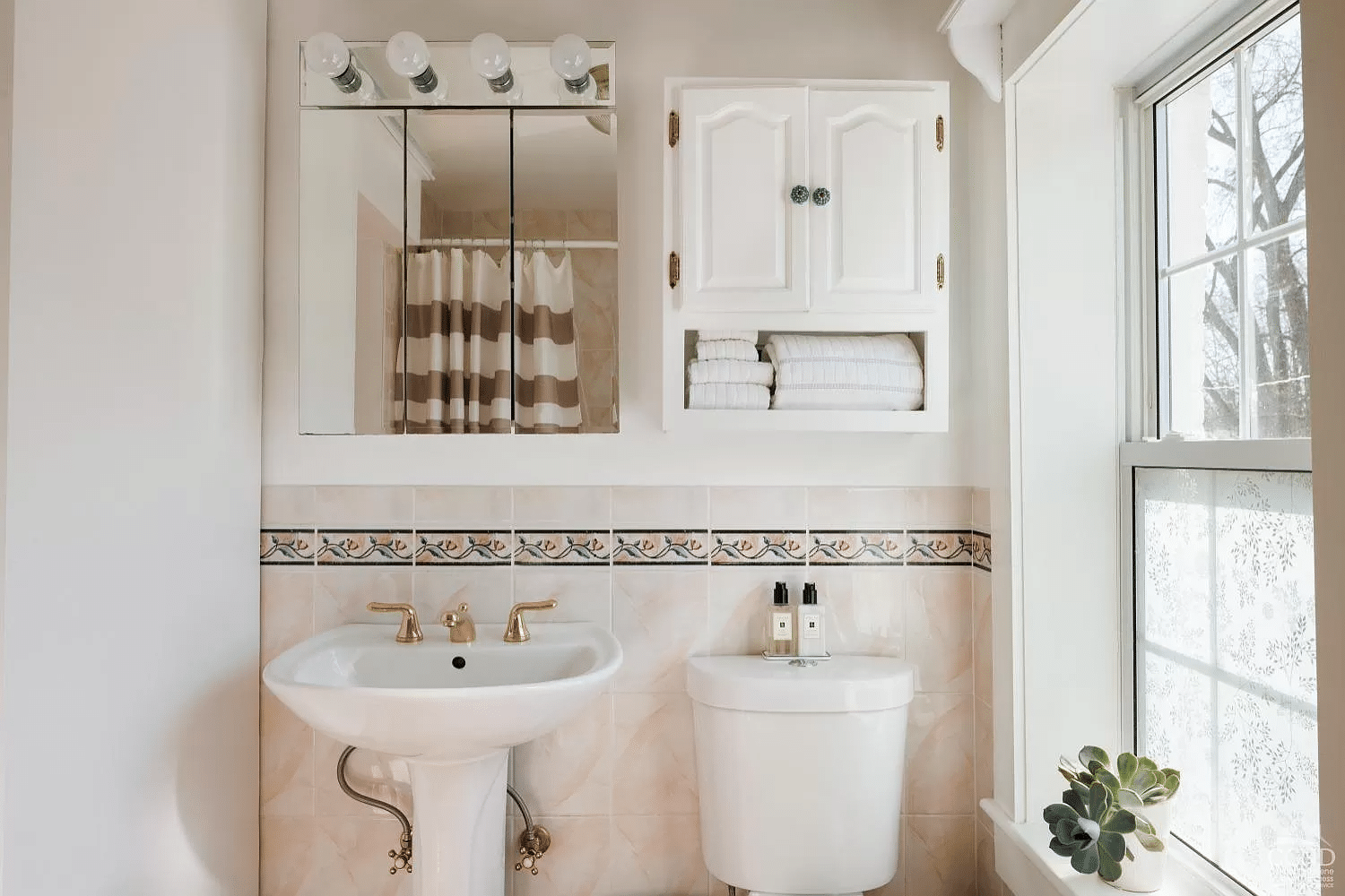 bathroom with floral border tile, white fixtures