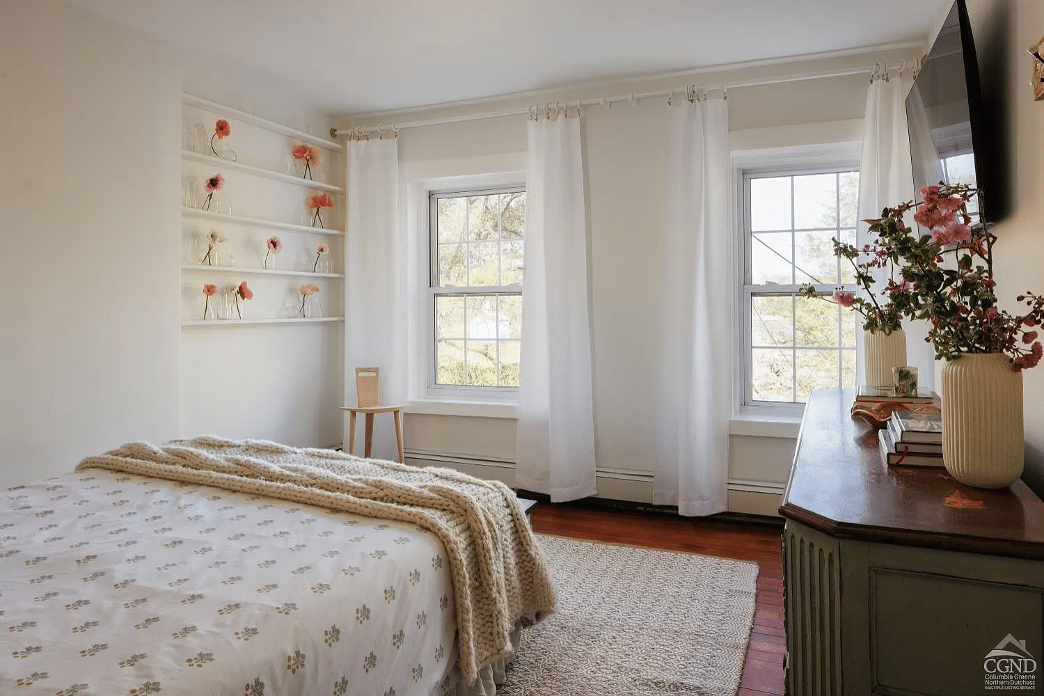 bedroom with two windows, built-in shelves, baseboard heating