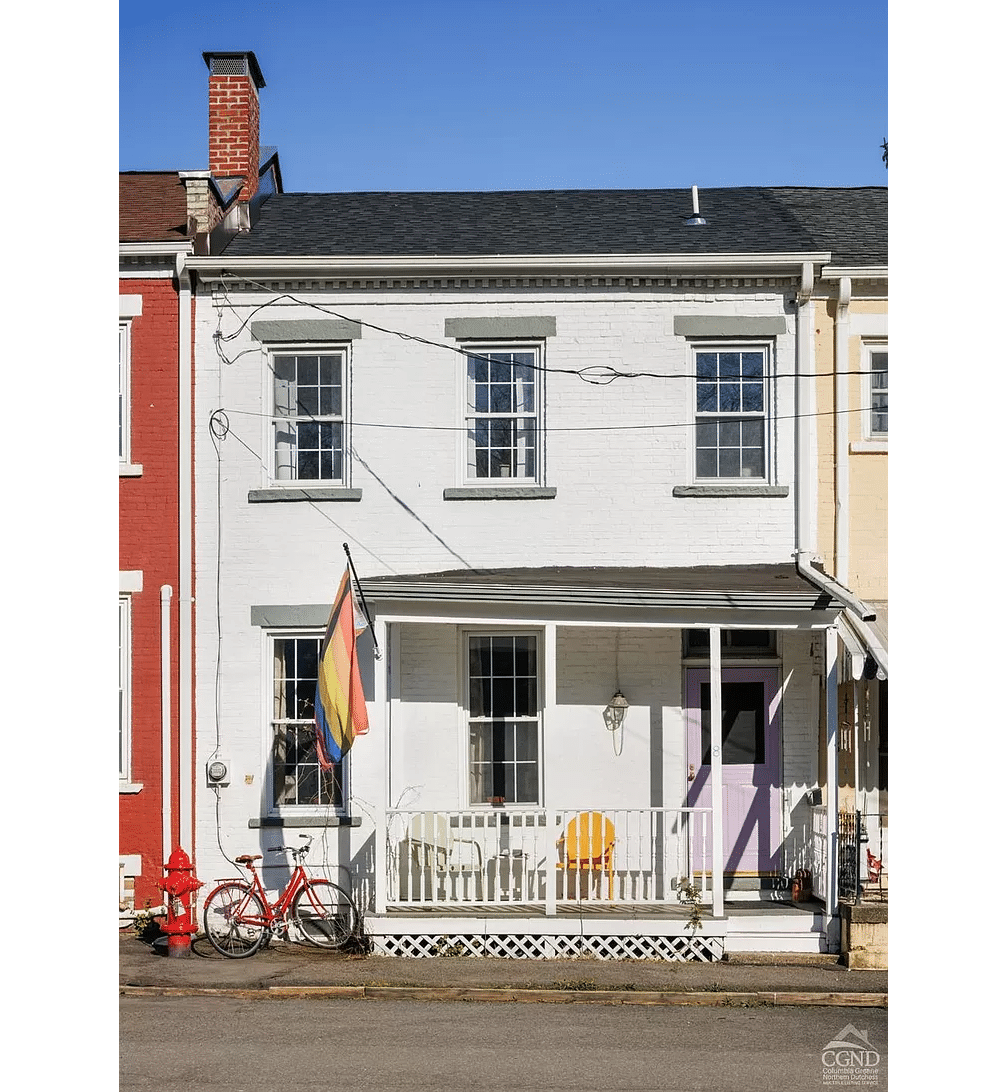 brick row house painted white with a porch and a purple door