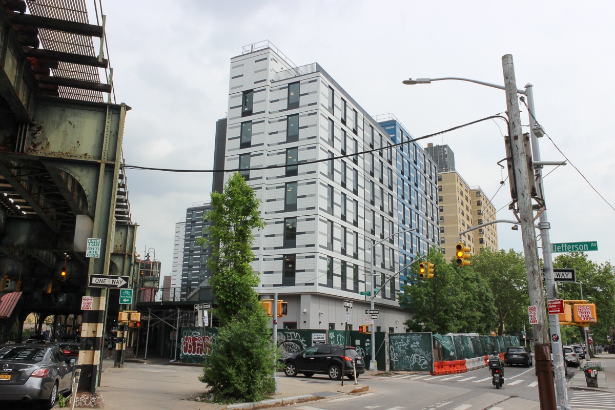 view of the building surrounded by construction fence and next to the elevated tracks