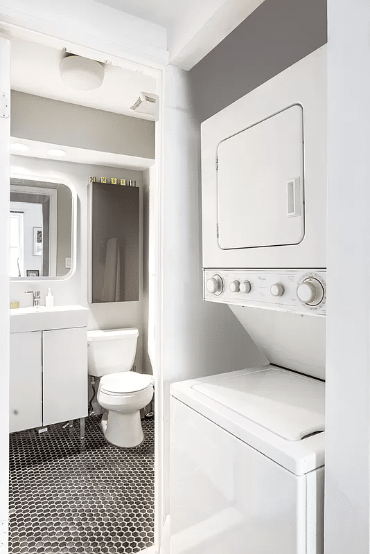 closet with in-unit laundry and view of bathroom with white fixtures beyond