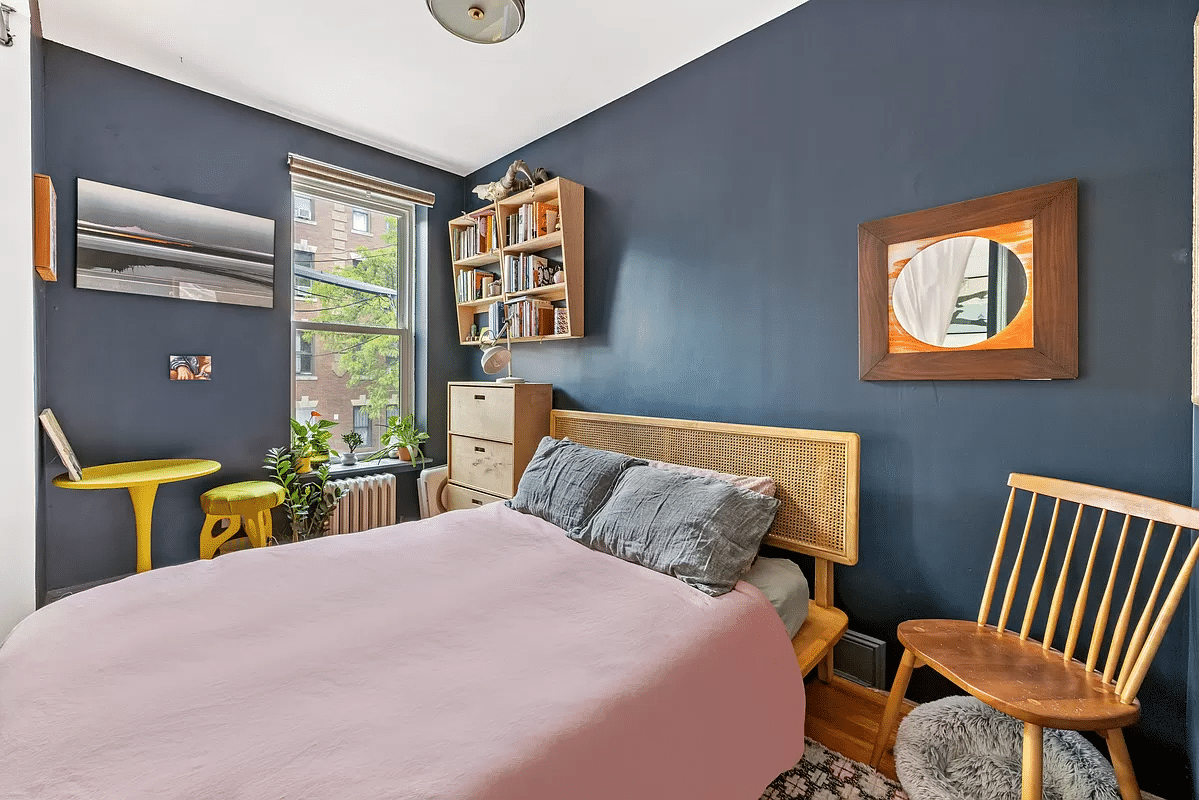 bedroom with dark blue walls, wood floor, window