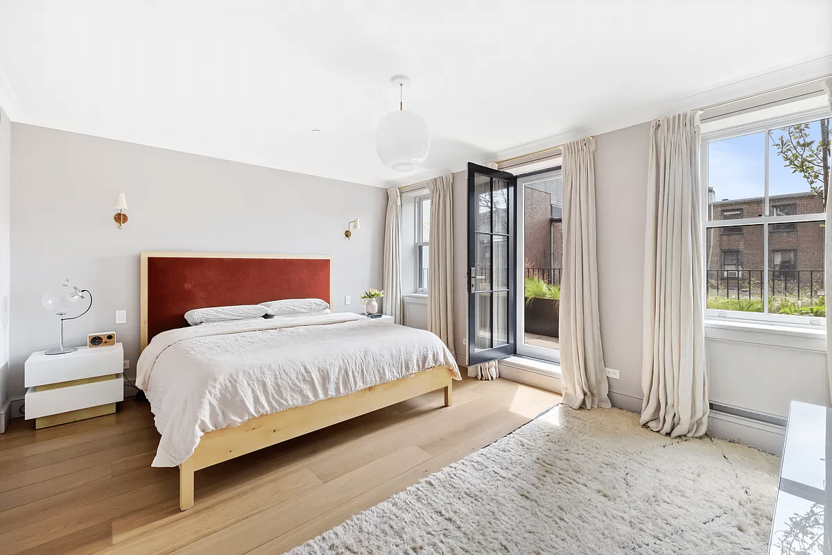 bedroom with pale wood floors and glass door to terrace