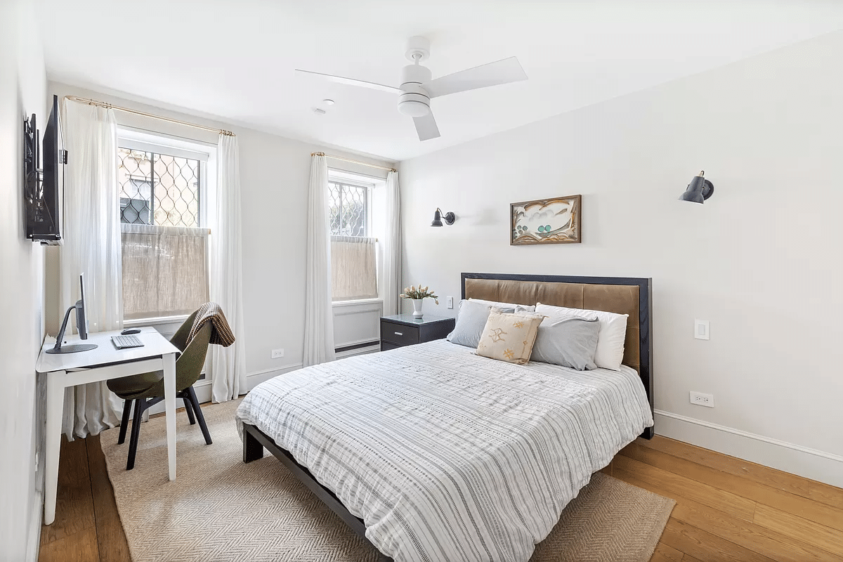 bedroom on the garden level with white walls and a ceiling fan