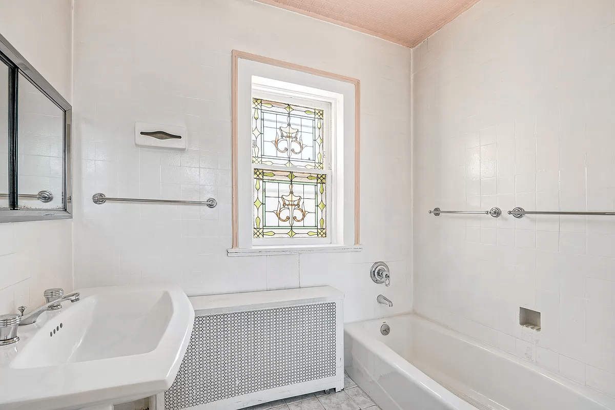 bathroom with white fixtures and a stained glass window