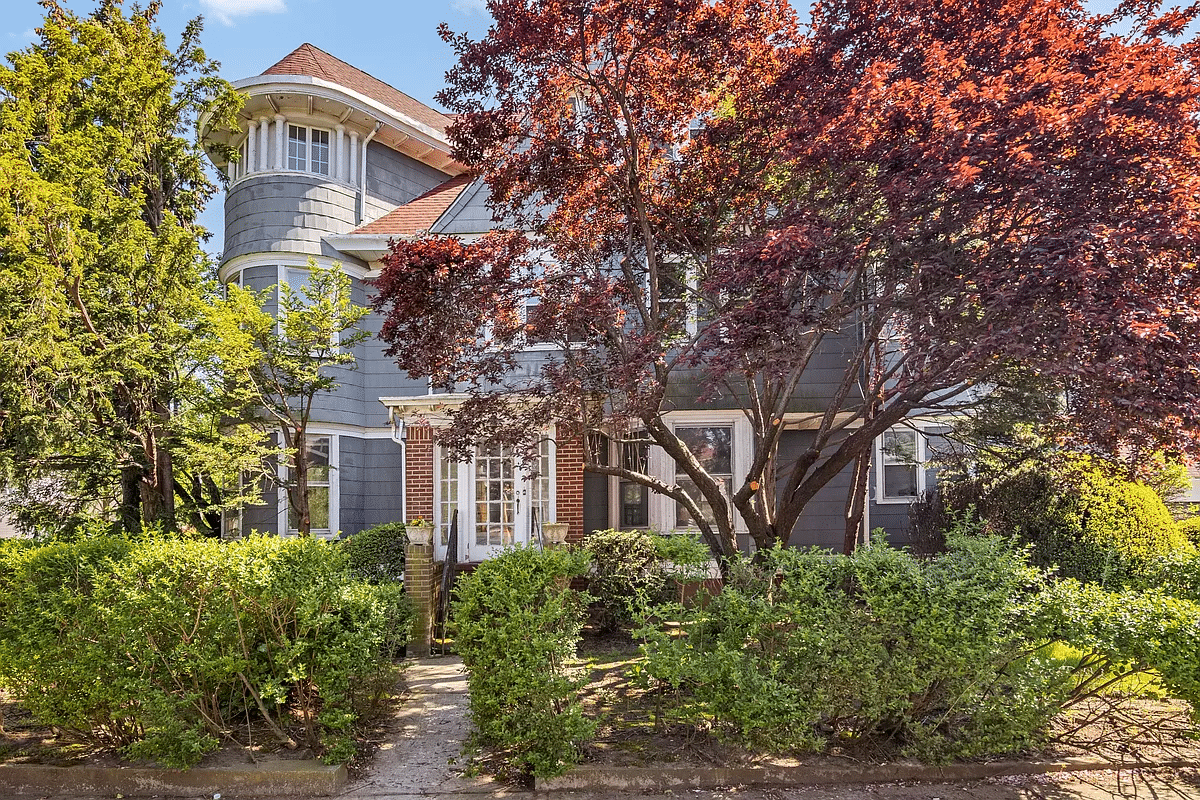 exterior of the house with white trim, bay windows and a brick vestibule