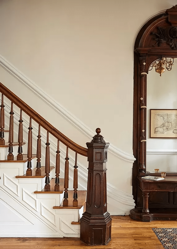 entry with original stair with newel post, mirror, wood floor