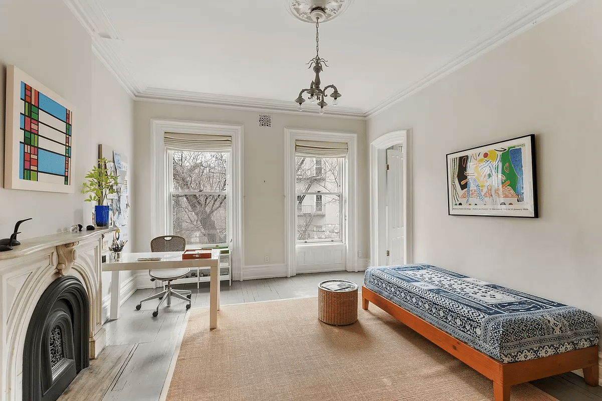 bedroom with wood floor painted gray and a marble mantel set up as an office