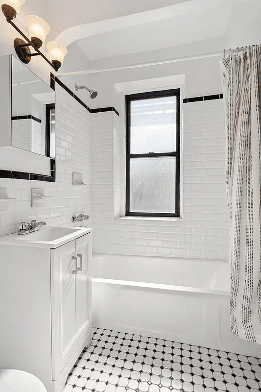 bathroom with white fixtures and black and white tile