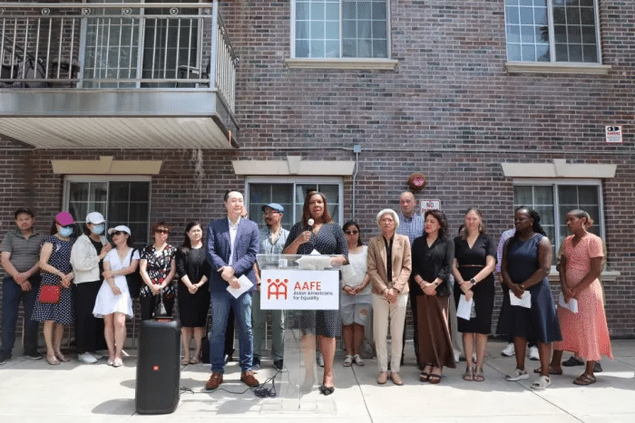 group gathered behind a podium in front of the building