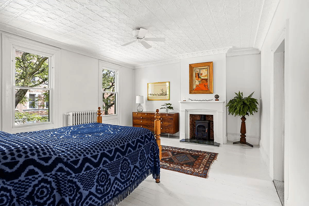 a bedroom with tin ceiling and wood floors painted white