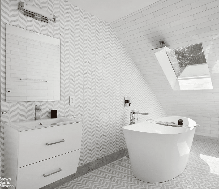 bathroom with skylight, white and gray tile, soaking tub