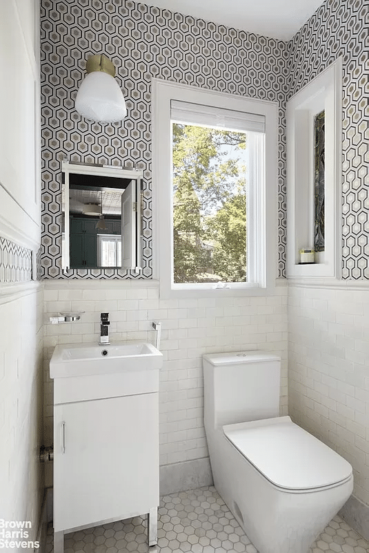 bathroom with wallpaper above white subway tile, white fixtures