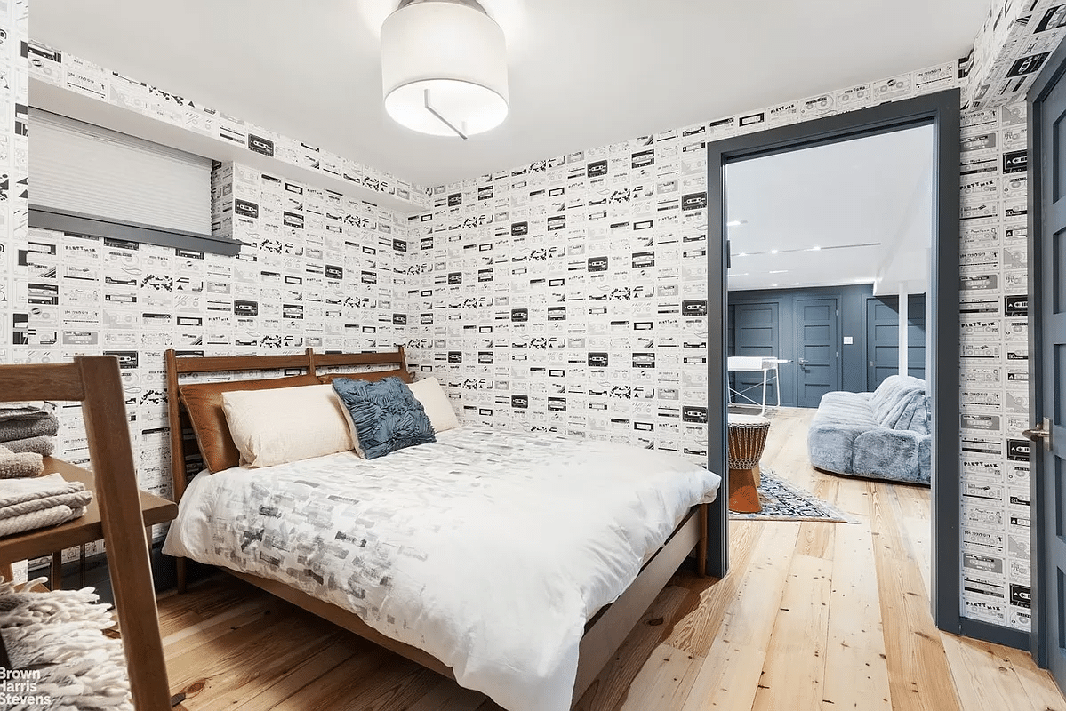 bedroom in basement with black and white wallpaper, wood floor