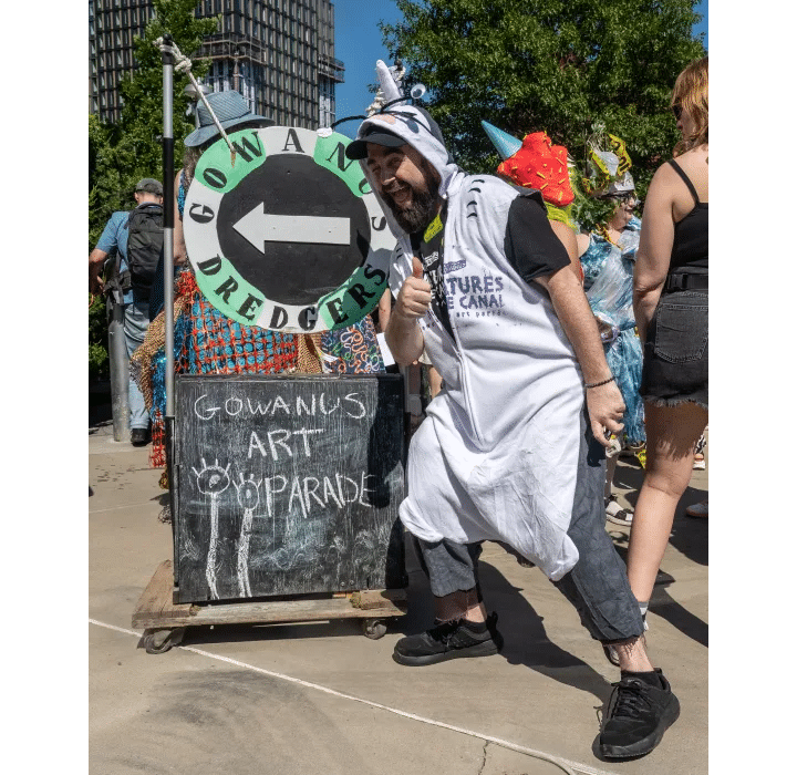 person posing by a sign for the parade