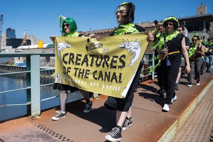 people holding a banner for creatures of the canal