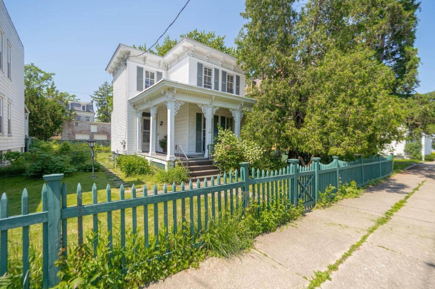 exterior of the white clapboard house with shutters and a picket fence