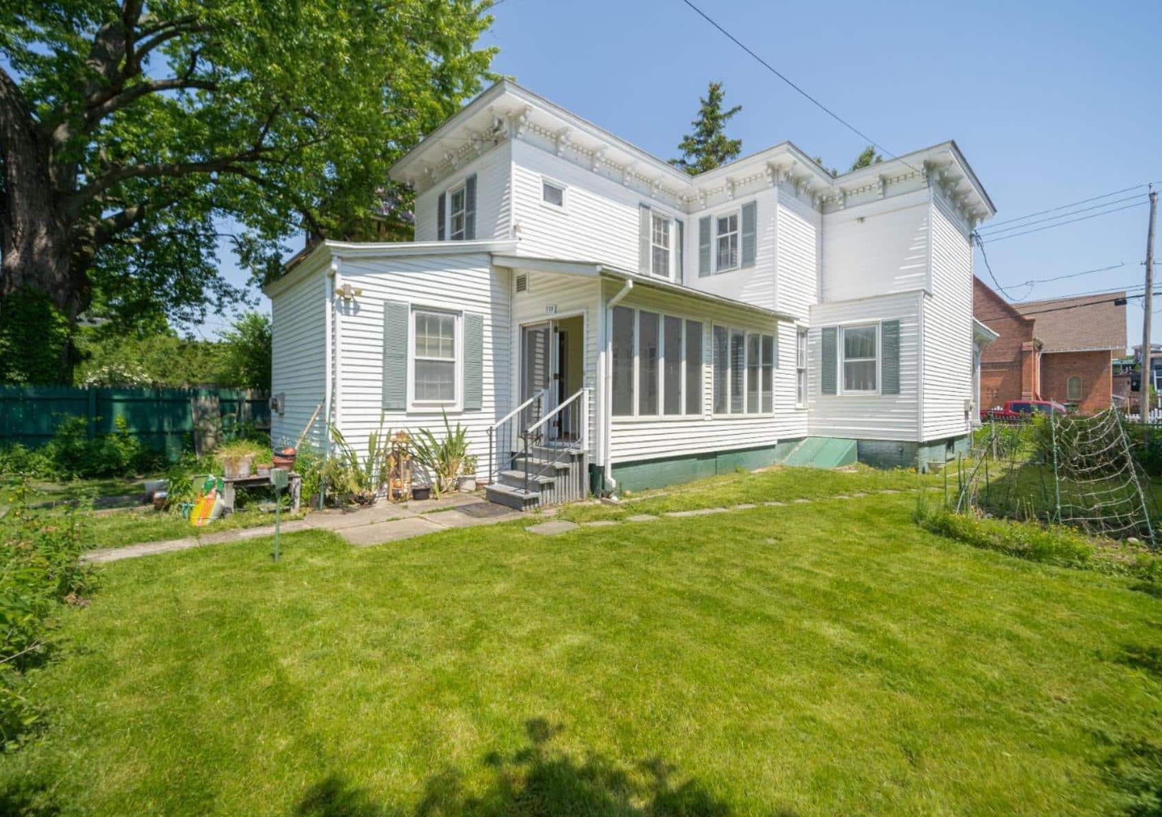 view of the rear facade of the white clapboard house with an enclosed side porch