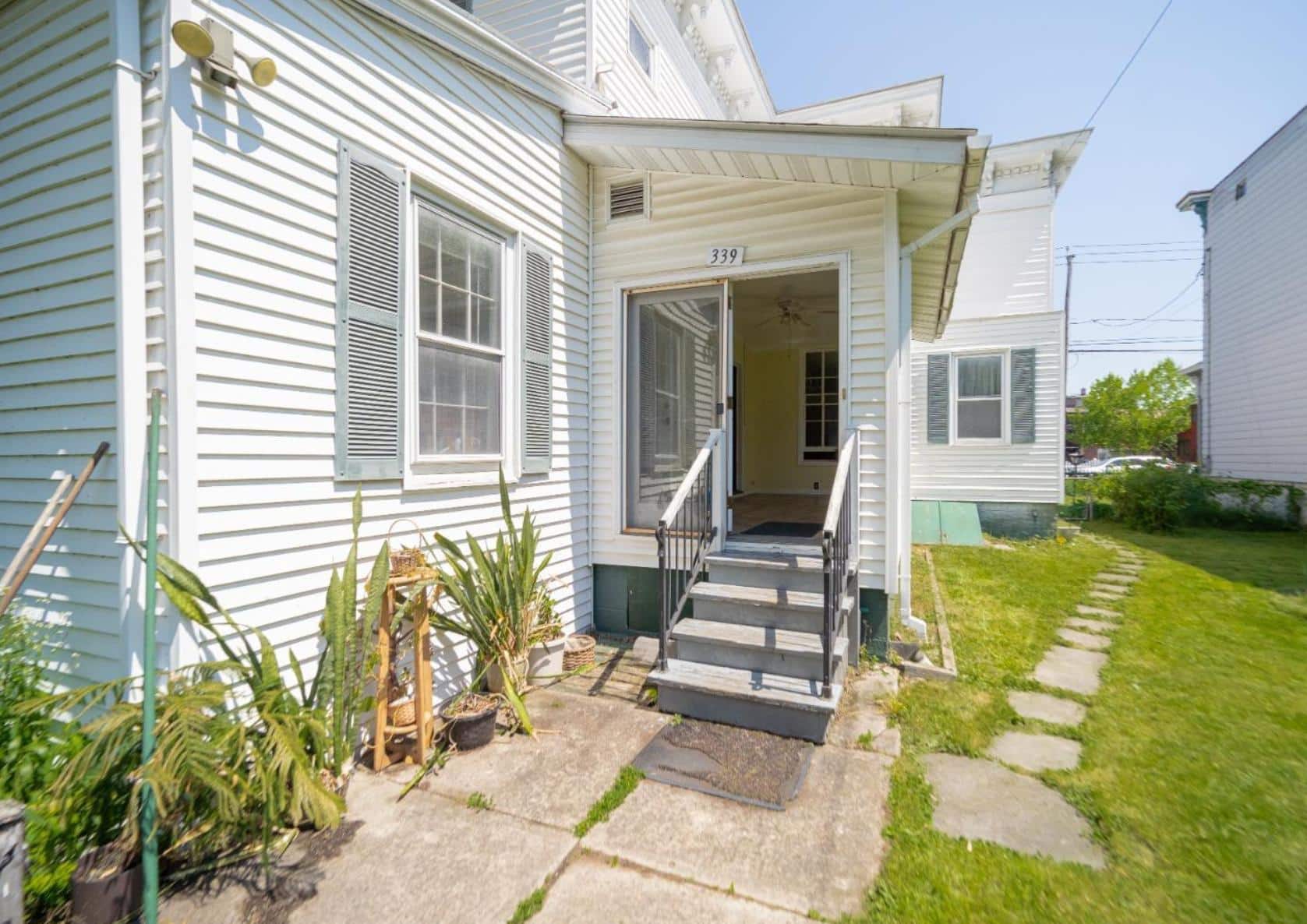 view of the rear facade of the white clapboard house with an enclosed side porch