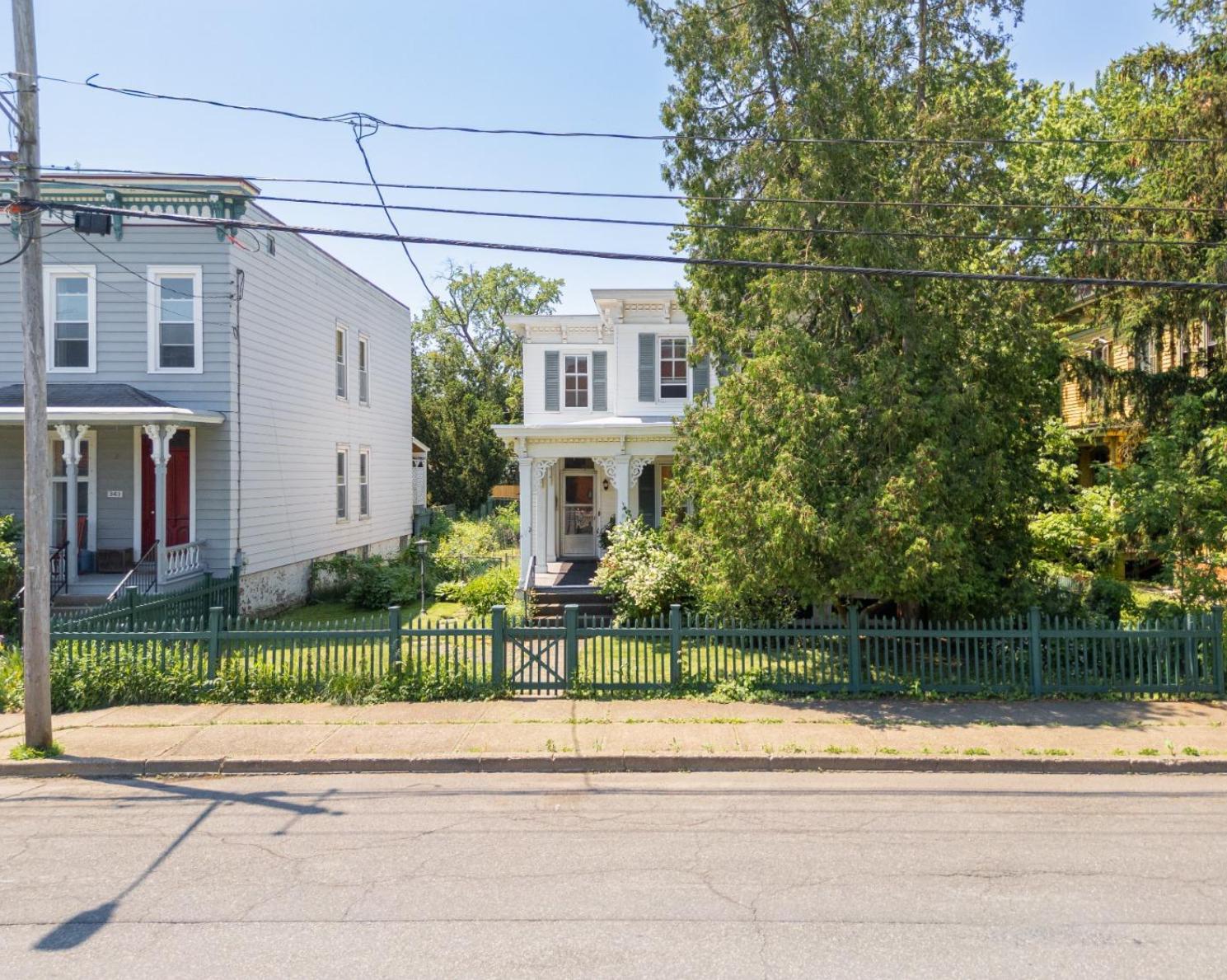 exterior of the white clapboard house with shutters and a picket fence