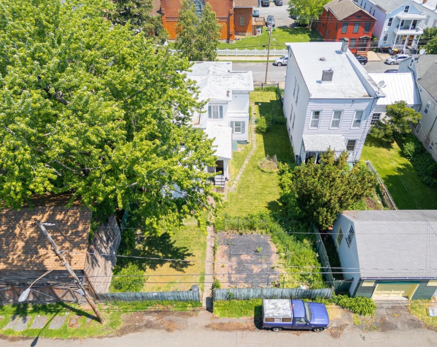 aerial view of the rear facade of the white clapboard house a rear entrance and a fenced-in yard