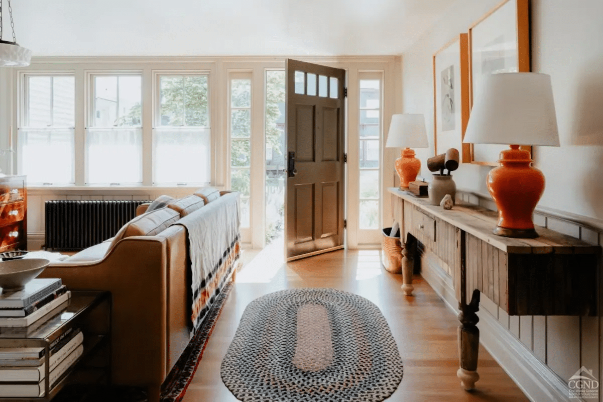 front door open to the living room with wood floors, wainscoting