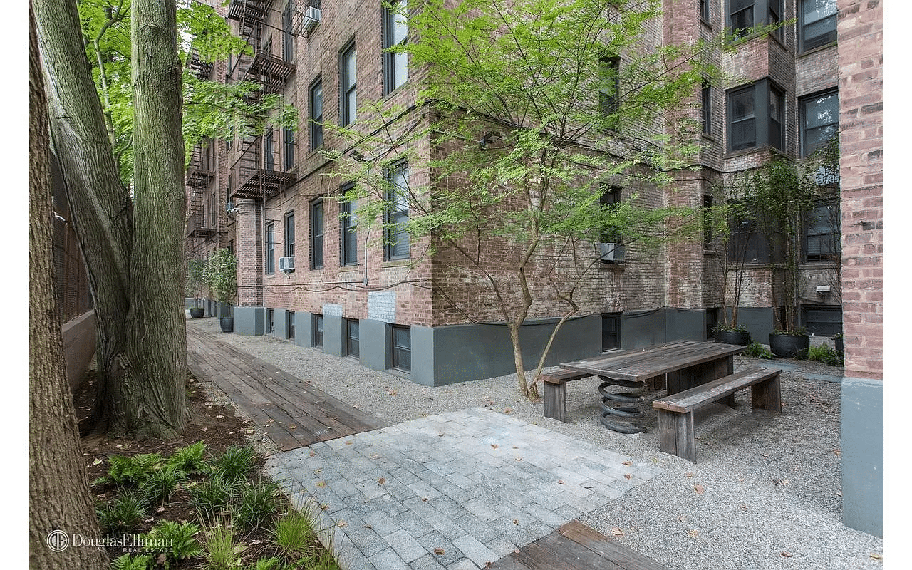 rear courtyard fo the building with a picnic table and trees