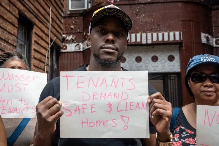 tenant holds a sign demanding safe homes