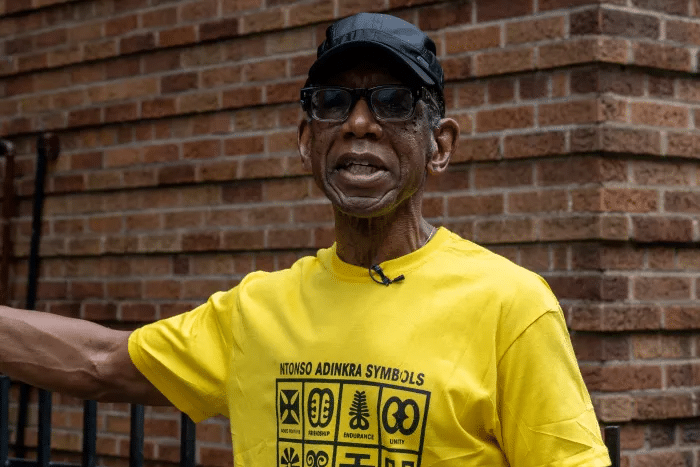 man in yellow shirt stands outside the building