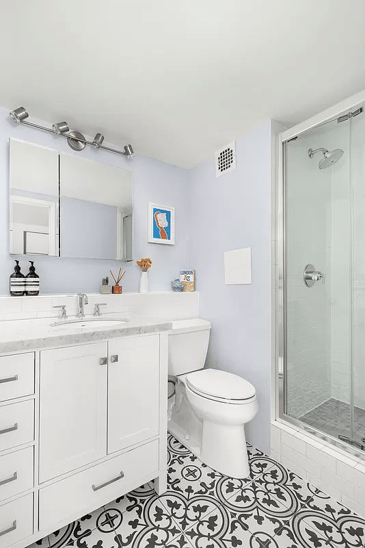 Bathroom with black and white floor tiles, white fixtures, and shower