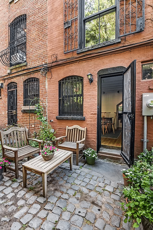 paved rear yard with door open and view into dining room