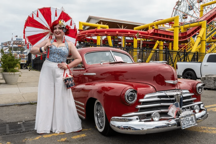 woman posing in front of a red car