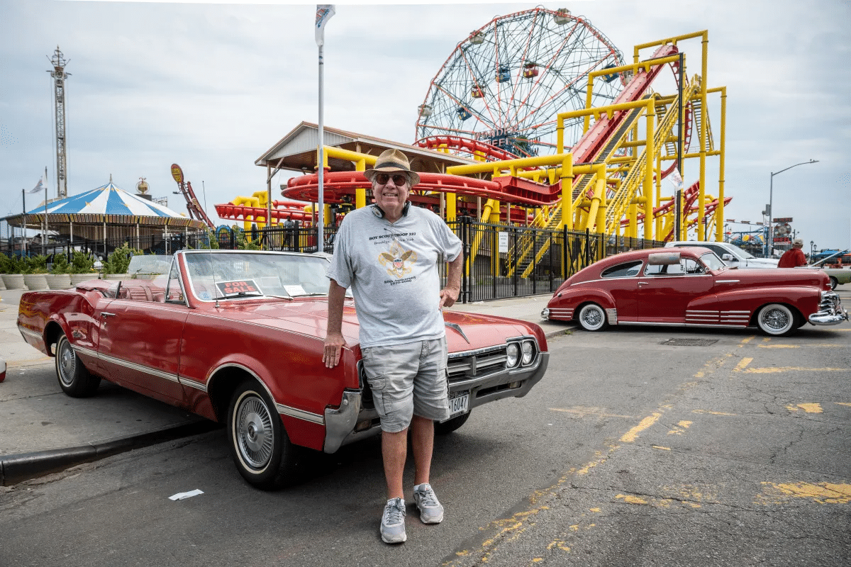 coney island - man posing in front of a red convertible