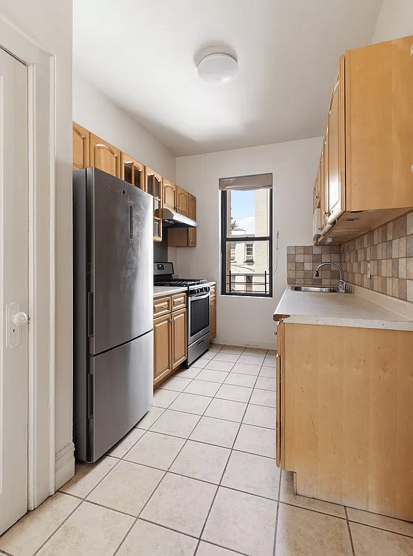 kitchen with beige tile floor and backsplahs, wood cabinets