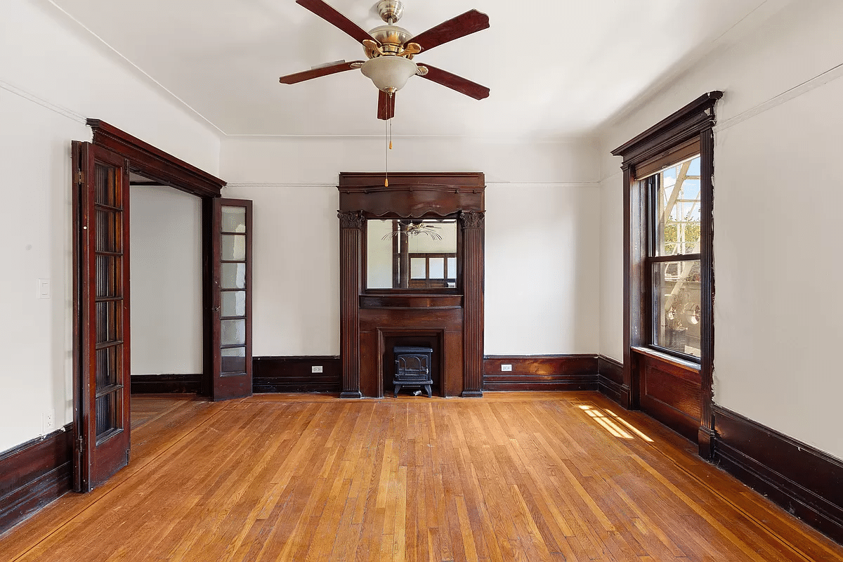 living room with wood floor, mantel and a ceiling fan