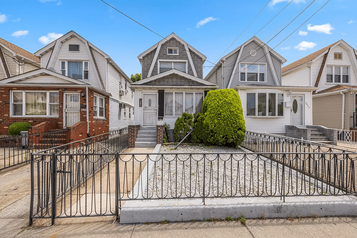 standalone house with fence around a gravel filled front yard