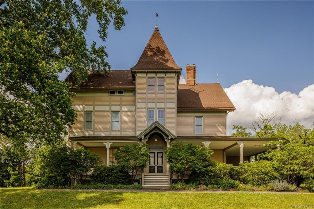 front of the wood villa with tower and pale, painted clapboard