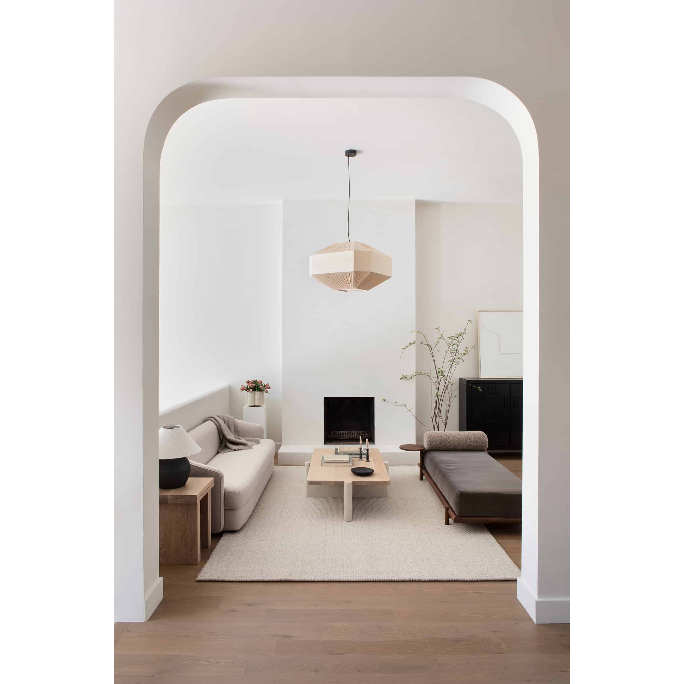 curved doorway with view into living room with white walls, fireplace 