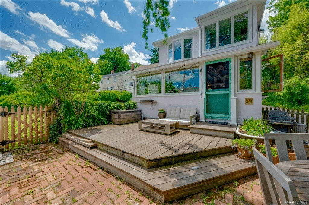 rear facade with wood deck with steps down to brick paved patio