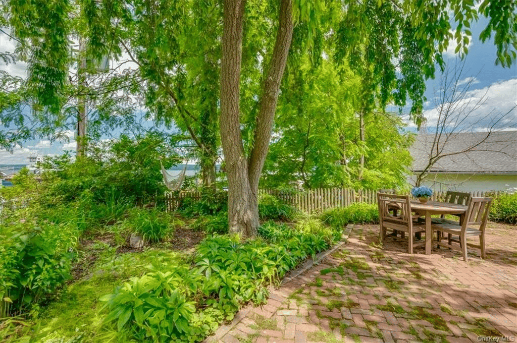 garden with brick paved patio and a planting bed with tree