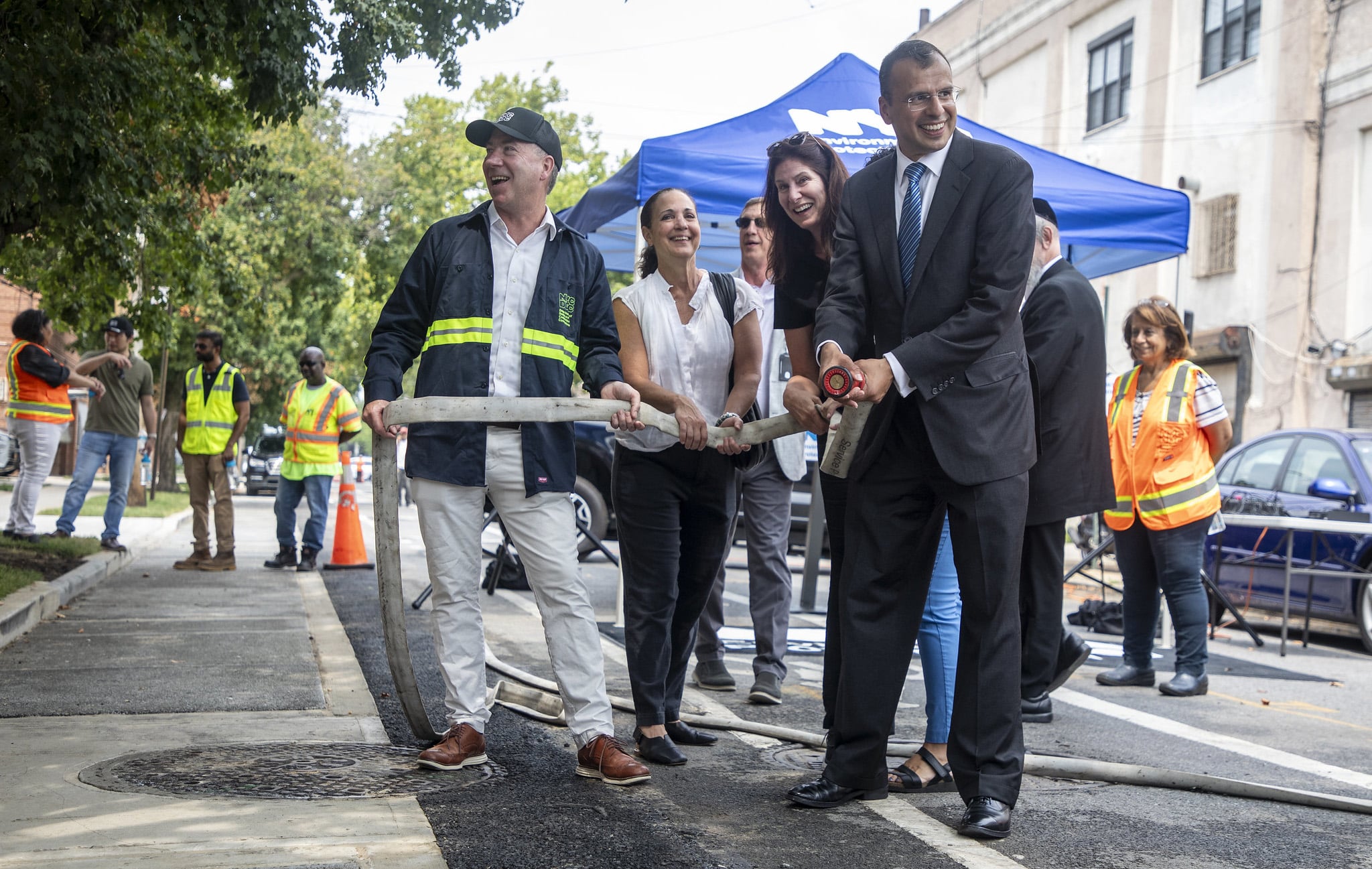 porous pavement - group of people holding a water hose over pavement