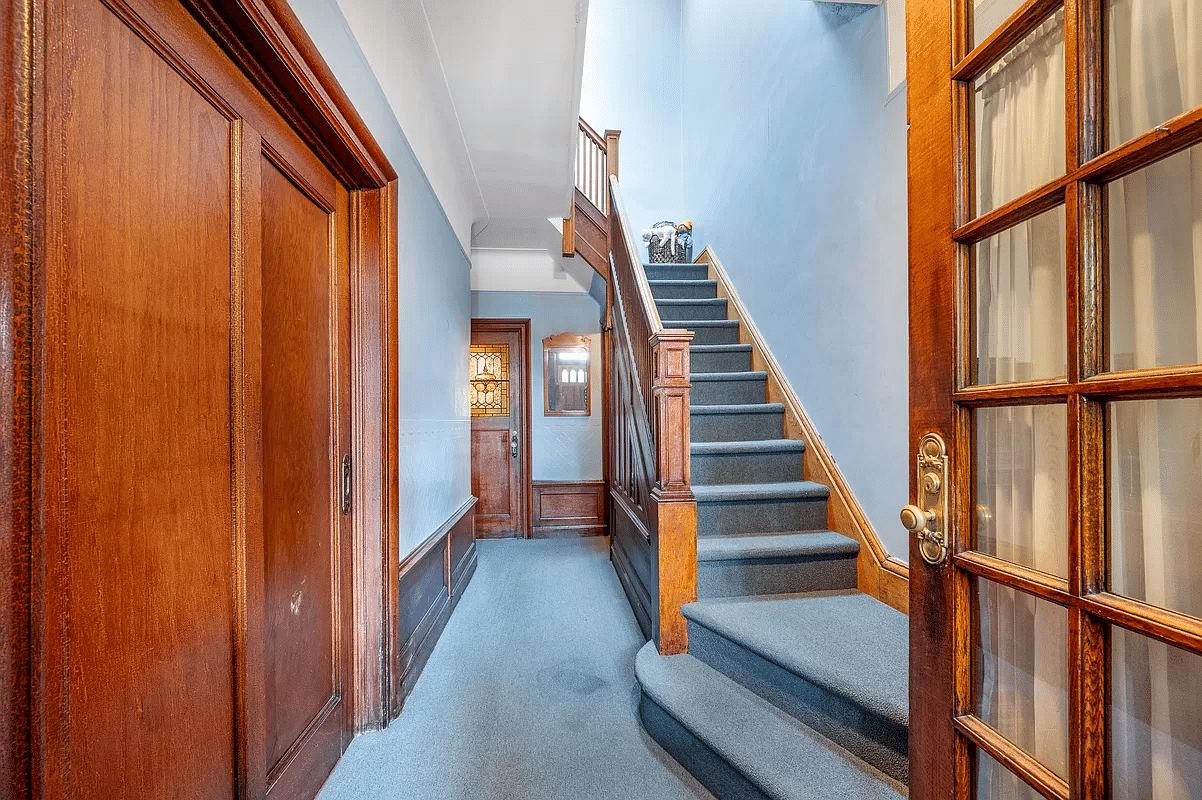 Entrance with blue carpet, original staircase