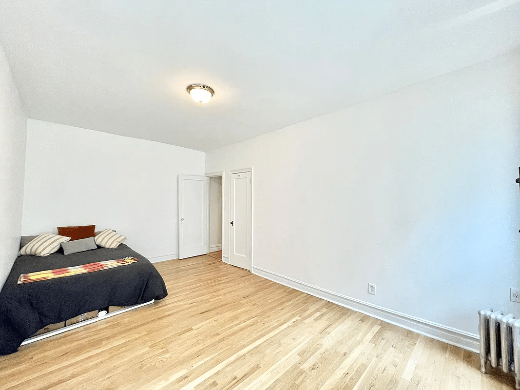 bedroom with wood floor, white walls and a closet